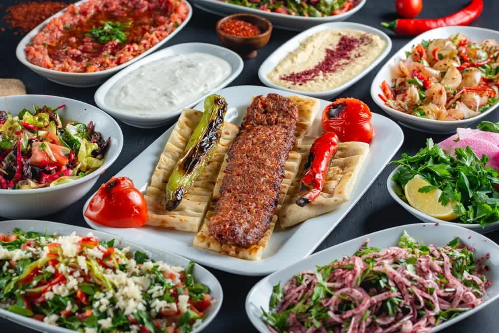 Adana kebabı ve salatalarla hazırlanmış restoran sunumu